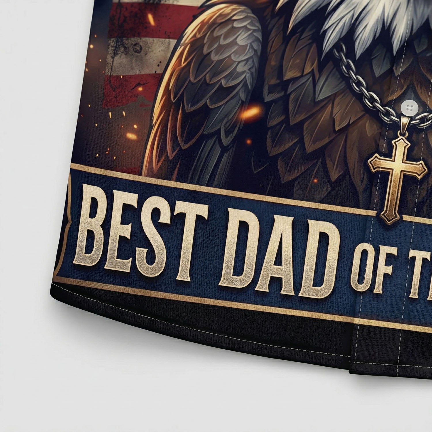Extreme close up of the high quality print on the patriotic shirt showing the Best Dad Of The Nation banner and the golden cross necklace detail