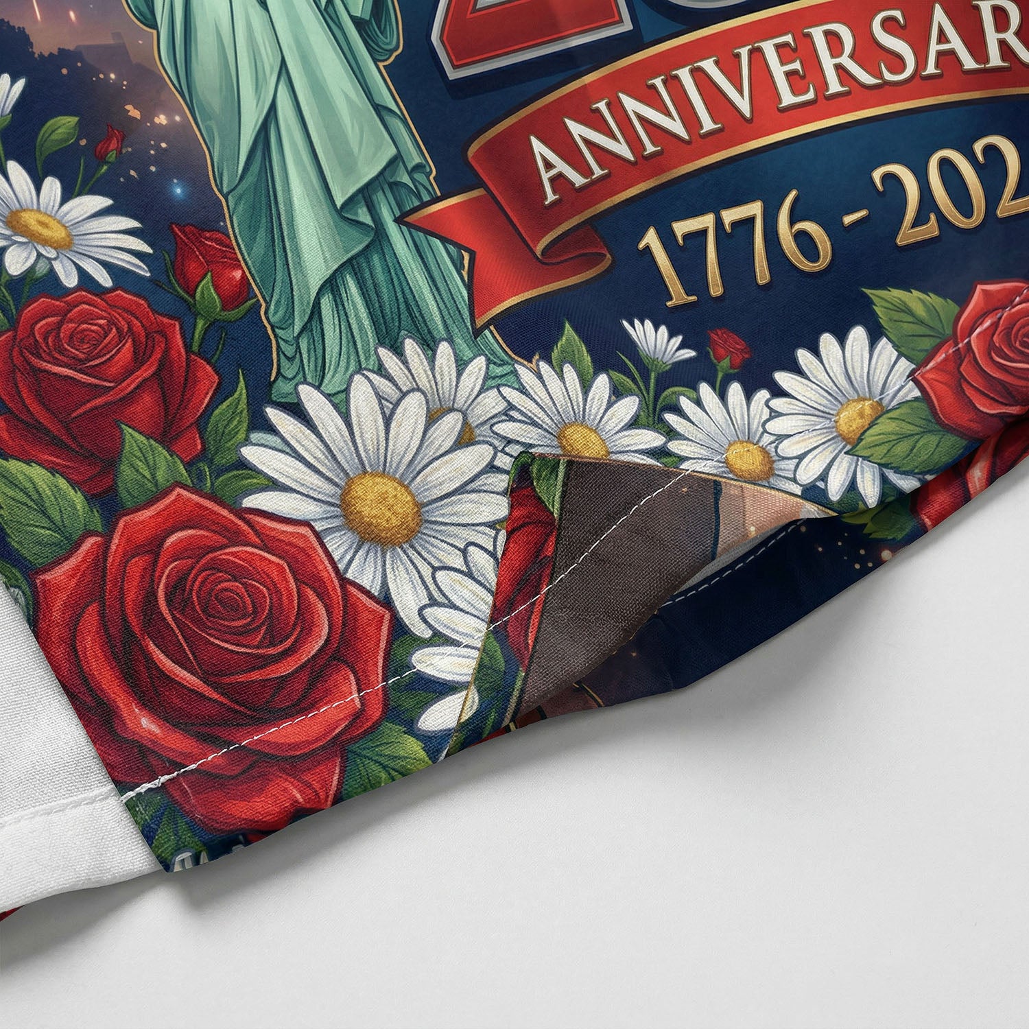 Macro shot of red roses, white daisies, and the Statue of Liberty print on the hem of the patriotic anniversary shirt.