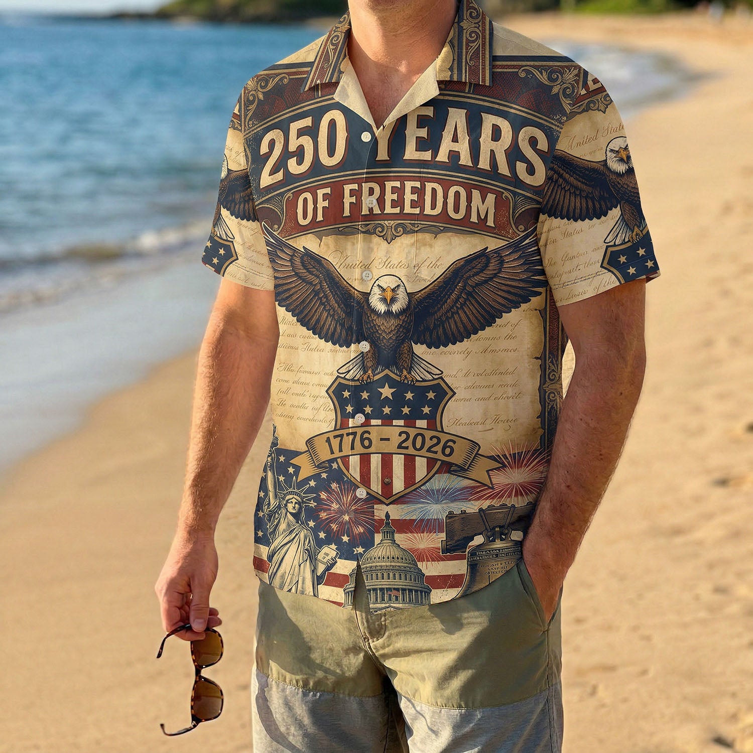 A male model wearing the white USA 250th anniversary patriotic shirt on a sunny beach showcasing a classic American summer look for the US birthday