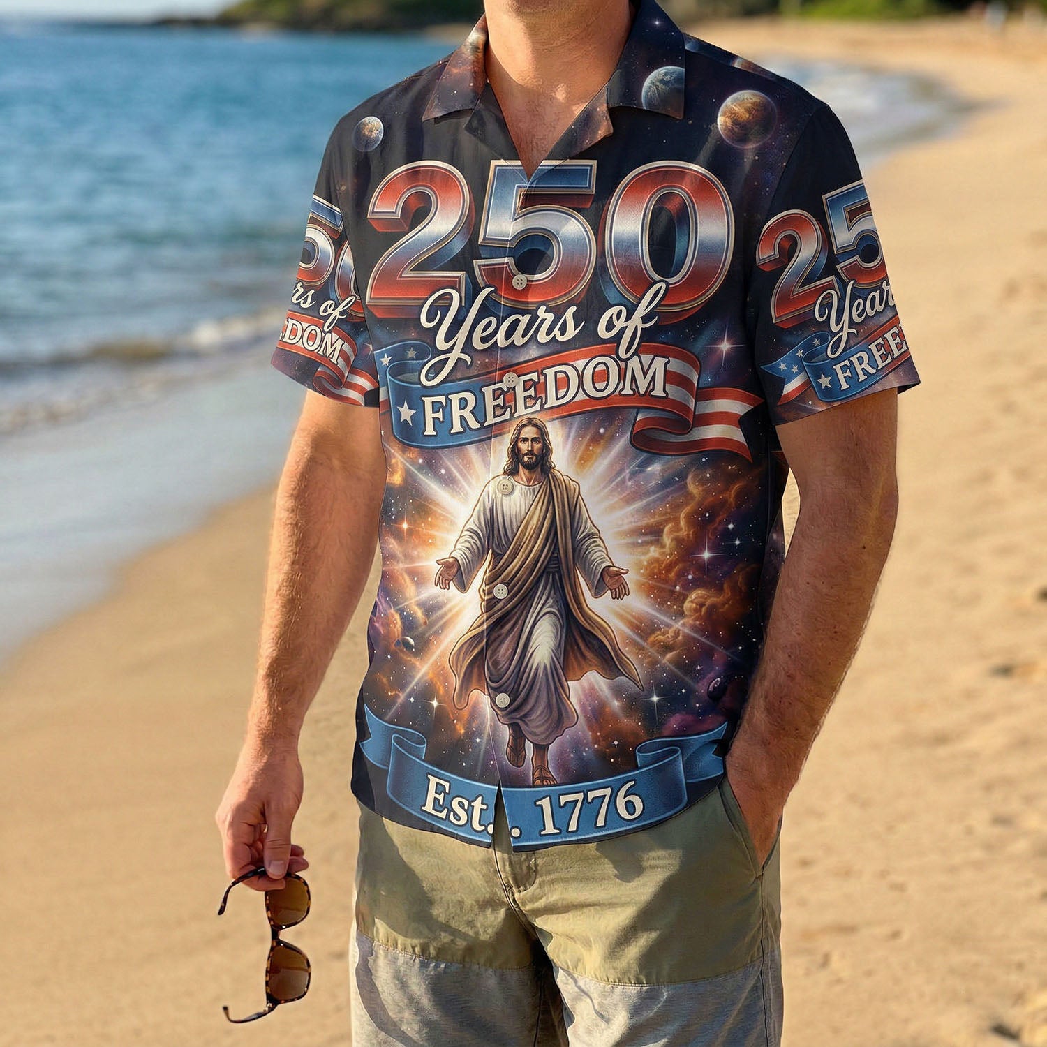 A man wearing a patriotic religious shirt on a sunny beach, highlighting the summer style for the US 250th celebration.