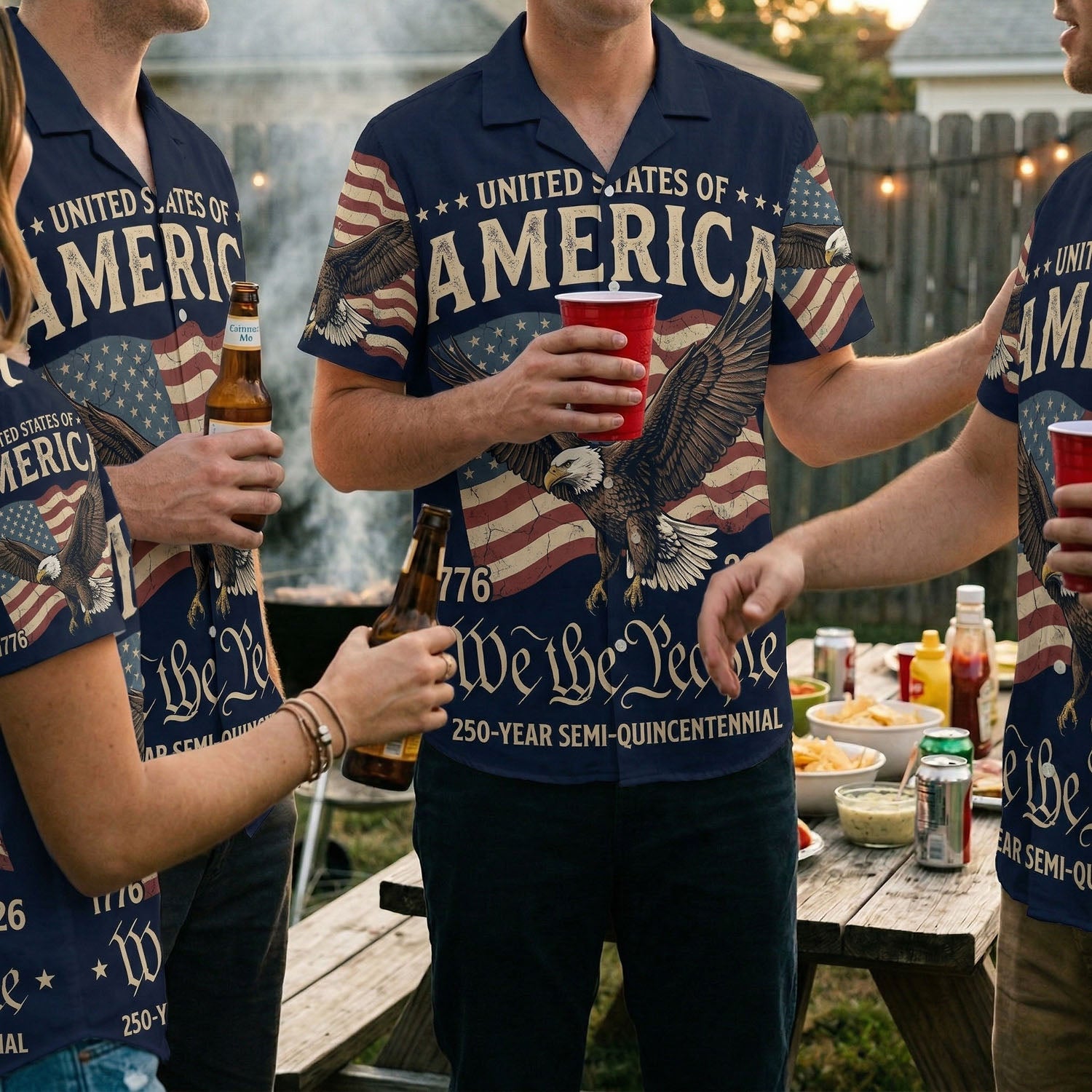 A group of friends wearing matching America The Beautiful patriotic shirts at a backyard BBQ celebration for the US 250th anniversary