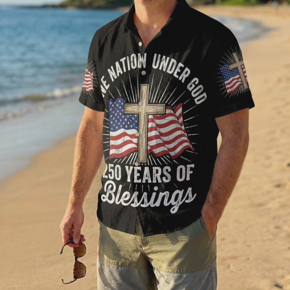 A male model wearing the black One Nation Under God Aloha shirt on a sunny beach, showcasing a comfortable summer holiday style.